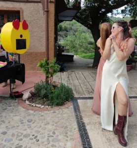 fotomaton con cara de emoji y chicas posando delante para hacerse fotos